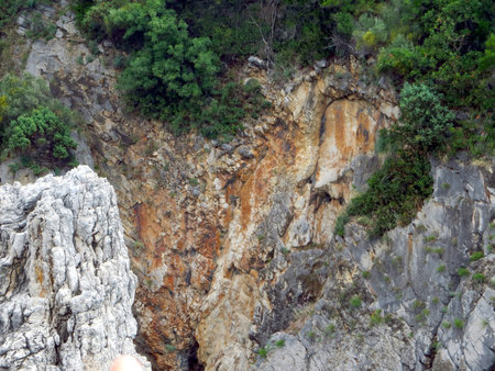 Coastal landscape of Montenegro features rocky cliffs descending into the Adriatic Sea with greenery enhancing the natural beauty of the rugged terrain during daylight.の写真素材