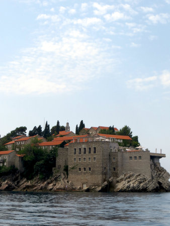 Sveti Stefan island resort showcases elegant stone buildings among lush greenery overlooking serene waters. Visitors enjoy breathtaking views and the Mediterranean atmosphere.の写真素材