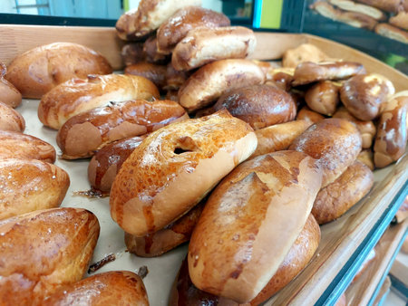 Soft, golden rolls are neatly arranged on a wooden tray in a bustling bakery. The warm, inviting aroma fills the air as bakers prepare for the lunch crowd.の写真素材