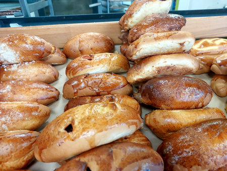 Freshly baked rolls are carefully arranged on a wooden tray in a warm kitchen. The golden-brown texture and aroma fill the air, enticing everyone nearby.の写真素材