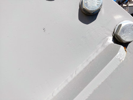 Details of a metallic flange secured with bolts and nuts are captured in a bright industrial environment, showing the components structural integrity and design.の写真素材