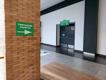Directional signs in green provide clear guidance to a temporary shelter within a shopping mall in...