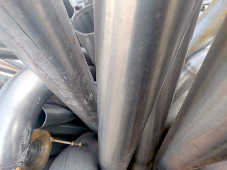 Pipes and metal scraps made of stainless steel are stacked closely together in a recycling yard...