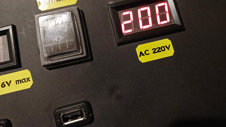 A close view of an electrical panel showing an indicator, charging station, and digital display...