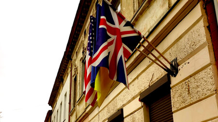 Three flags hang on a wall of a historic building. The flags represent the USA, Ukraine, and Great...