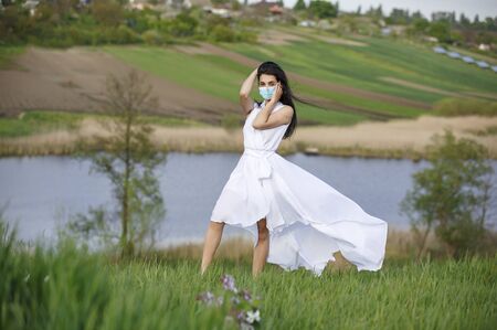 Girl in white dress and medical mask. Nature backgroundの写真素材