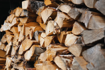 Stacked firewood of pine and birch prepared for the fireplace and stove in a large log woodpile in the yard.の写真素材