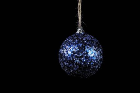 Close-up glistening blue ball on black background, Christmas and New Year decoration on dark.の写真素材