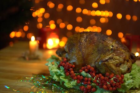 Roasted bird on platter with salad stands on a table amidst yellow electric lights with a festive Christmas dinner .の写真素材