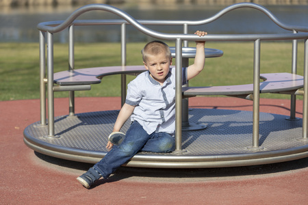 Little boy on a playground. Child playing outdoors in summer. Kids play on school yard. Happy kid in kindergarten or preschool. Children having fun at daycare play ground. Toddler on a swing.の写真素材