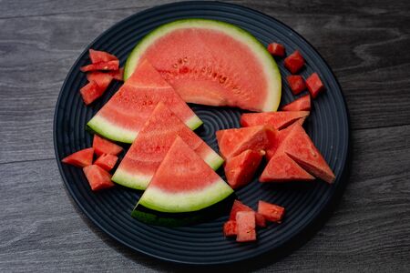 Slices of ripe watermelon in a plate on a dark backgroundの写真素材