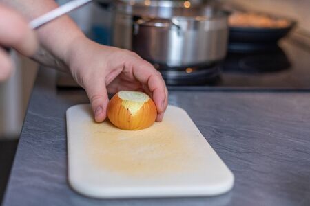 Cropped Hands Of Woman Cutting Onion On Cutting Board At Tableの写真素材