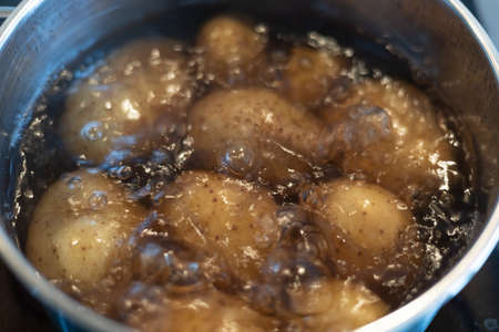 cooking potatoes in boiling water in a stainless steel pot on the stoveの写真素材