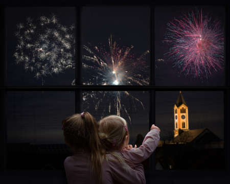 View through window of two kids watching fireworks, Happy new yearの写真素材