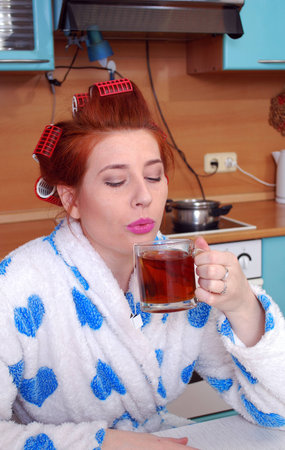 Young attractive red-haired woman drinking tea at kuhne.Duet on hot tea in a glass.の写真素材