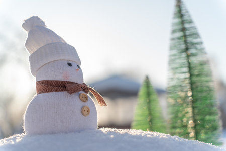 Figure of little cute snowman in a knitted hat and scarf on on snowy field in a sunny winter day. Concept for winter site head mockupcard or christmas card.の写真素材
