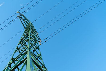 Power transmission line pylons with threatening blue clouds background