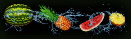 fruit - watermelon and pineapple in water on an isolated green and black backgroundの写真素材
