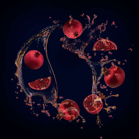 Juicy tasty pomegranate with splashes of juice background for designersの写真素材