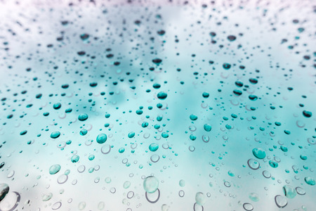 Water drops background. Water drops on glass window over blue sky.の写真素材