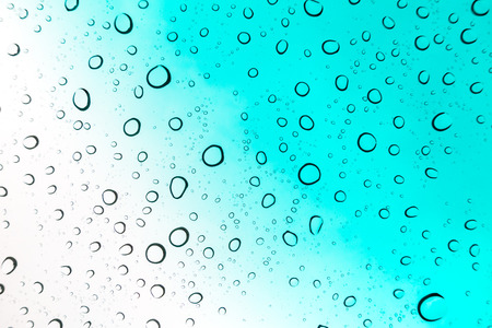 Water drops background. Water drops on glass window over blue sky.の写真素材