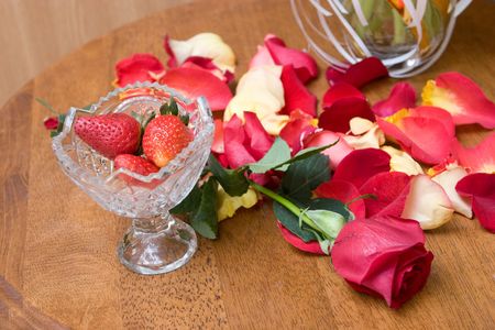 strawberry in a vase, red rose on the table and petals of red rosesの写真素材