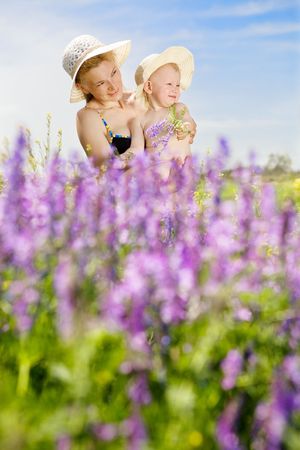 mother and small daughter on the sunny field of wild vetchの写真素材