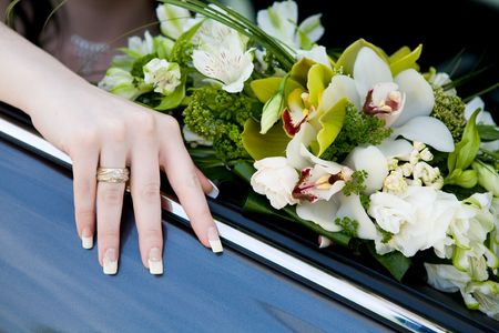 hand of the bride with wedding ring on the car and flower bouquetの写真素材