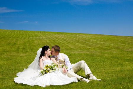 bride and groom kissing on the green grassの写真素材