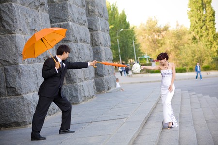 playing bride and groom with orange umbrellas の写真素材