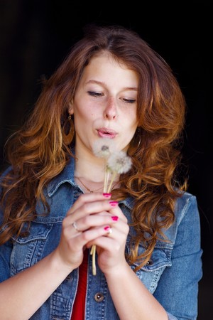 young girl blowing on two dandelionsの写真素材