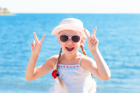 girl showing sign victory with fingers near seaの写真素材