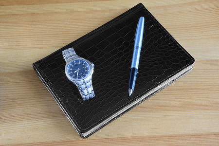 Watch and pen with a gold pen on a leather notebookの写真素材