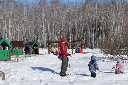 Parents with children are walking in the winter park. Children play with a dog in the snow. Photo - early spring of 2017, western Siberia.のeditorial素材