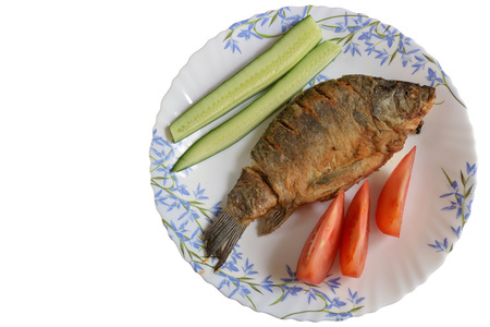 Fried fish (crucian) on a plate with tomatoes and cucumbers, isolated on white background.の写真素材