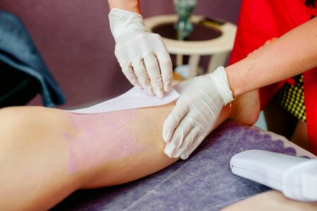 Beautician waxing female legs in spa centerの写真素材