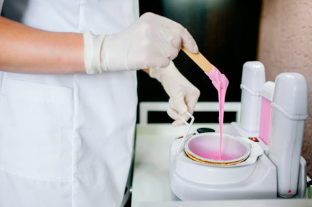 Preparation of pink wax for shugaring. Close-up wax for depilation is heated and melted in a round containerの写真素材