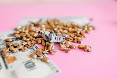 boat made of dollar on a pink background, golden grains of coffeeの写真素材