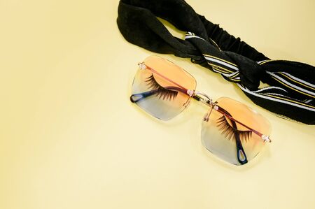 Flat lay of eyelashes and leaf on yellow background.の写真素材