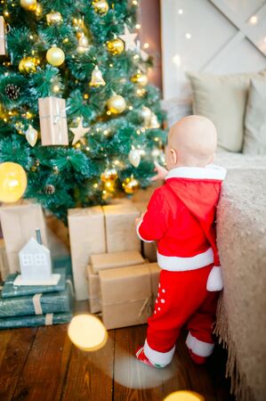 little boy with Santa costume decorates a Christmas tree. Christmasの写真素材