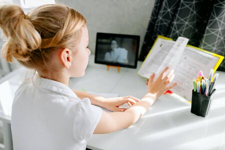 Schoolgirl watching online education class, happy talking with teacher on the internet at home.の写真素材