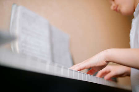 Pretty young musician playing classic digital piano at home during online class at home, social distance during quarantine, self-isolation, online education conceptの写真素材