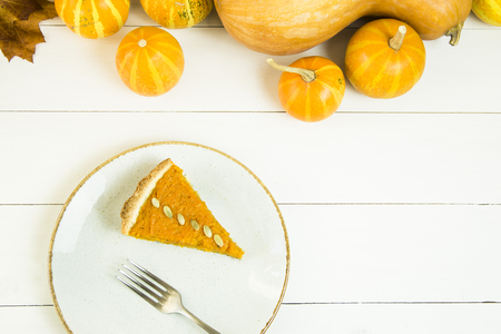 a slice of American pumpkin pie on Thanksgiving Day, decorated with pumpkin seeds. on a white tableの写真素材