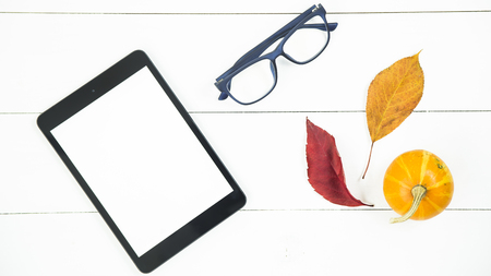 tablet with a white screen on the table next to the autumn leaves.の写真素材