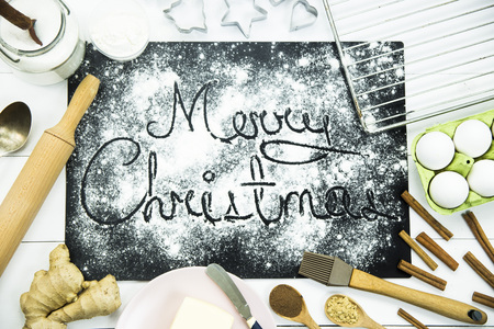 inscription Happy Christmas on a black board sprinkled with flour among the ingredients for baking ginger biscuitsの写真素材