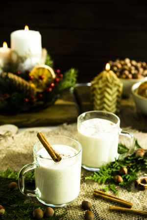 hot milk alcoholic drink   Egg-nog next to the Christmas candle and candlesの写真素材