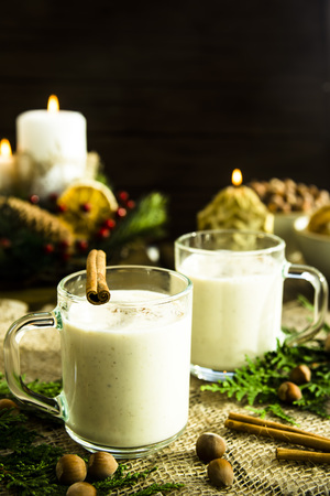 hot milk alcoholic drink   Egg-nog next to the Christmas candle and candlesの写真素材