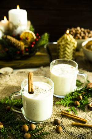 hot milk alcoholic drink   Egg-nog next to the Christmas candle and candlesの写真素材