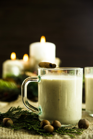 hot milk alcoholic drink   Egg-nog next to the Christmas candle and candlesの写真素材