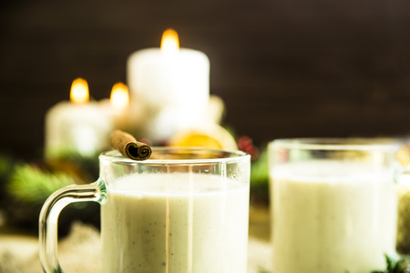 hot milk alcoholic drink   Egg-nog next to the Christmas candle and candlesの写真素材